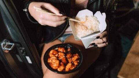 unrecognizable woman eating delicious takeaway asian dishes