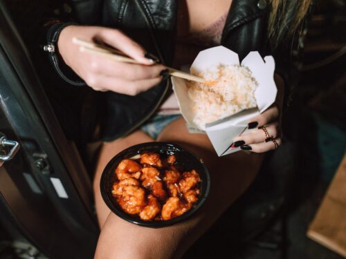 unrecognizable woman eating delicious takeaway asian dishes