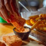 a person dipping a chicken nugget