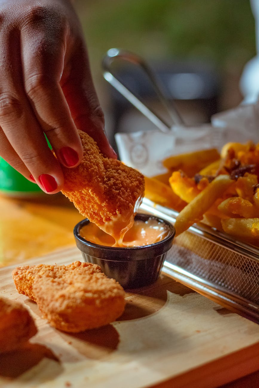 a person dipping a chicken nugget