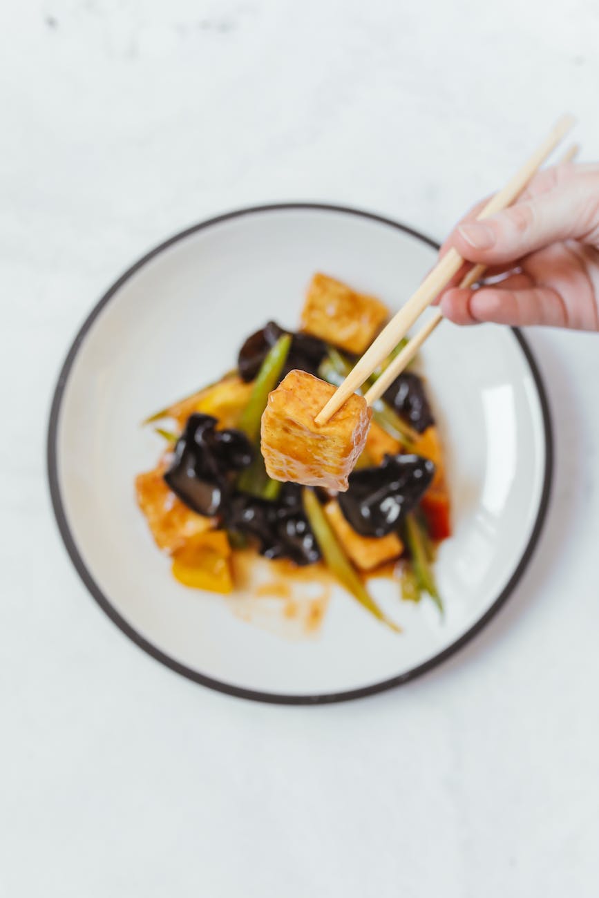 a person holding chopsticks with tofu