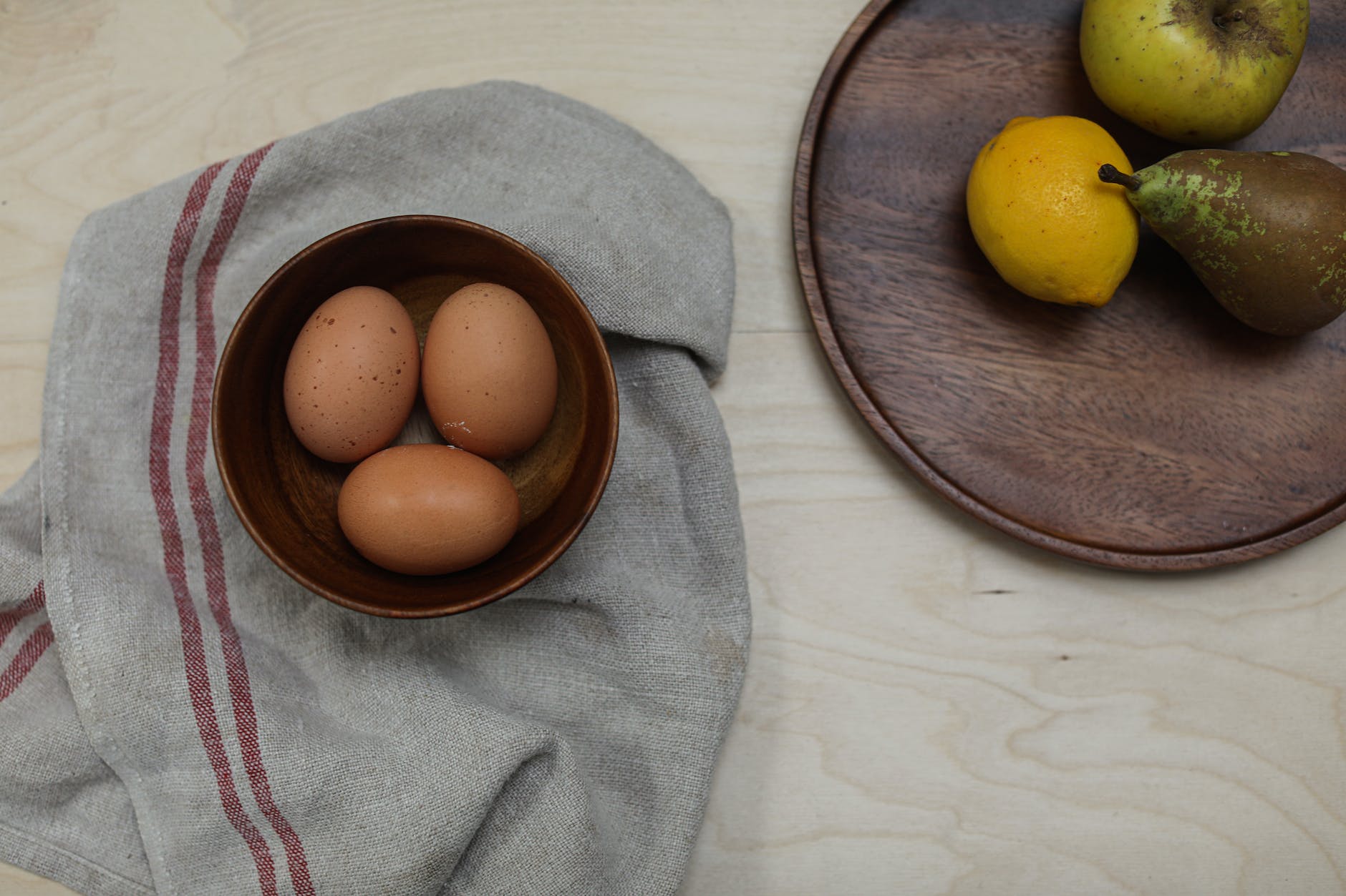 brown eggs in a bowl beside fruits on tray